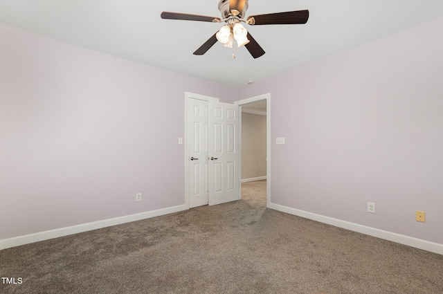 spare room featuring carpet floors, a ceiling fan, and baseboards