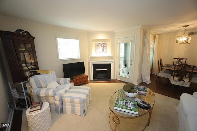 living area featuring crown molding, a fireplace, a chandelier, wood finished floors, and visible vents