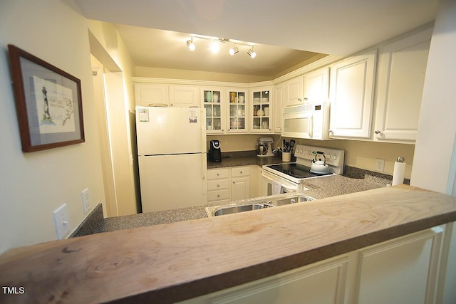 kitchen with white appliances, white cabinets, glass insert cabinets, and rail lighting