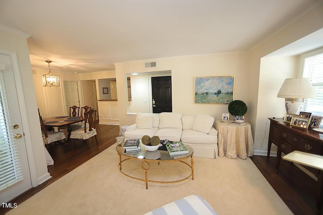 living area featuring visible vents, dark wood finished floors, crown molding, and a chandelier