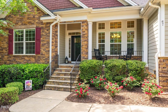 view of exterior entry with a porch and stone siding