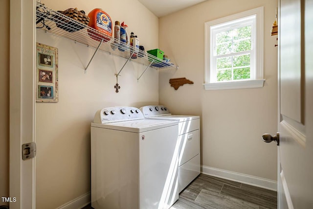 clothes washing area featuring baseboards, laundry area, wood finished floors, and washer and dryer