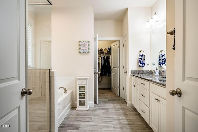 full bath featuring vanity, a garden tub, and a walk in closet