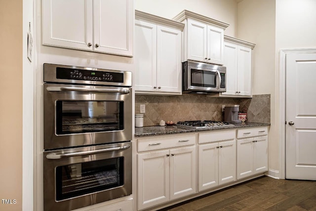 kitchen featuring decorative backsplash, stainless steel appliances, dark wood-style floors, and dark stone countertops