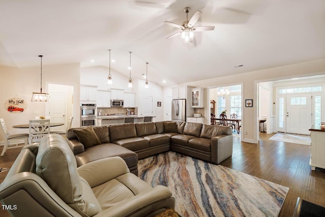 living area with baseboards, ceiling fan with notable chandelier, dark wood-style floors, and high vaulted ceiling