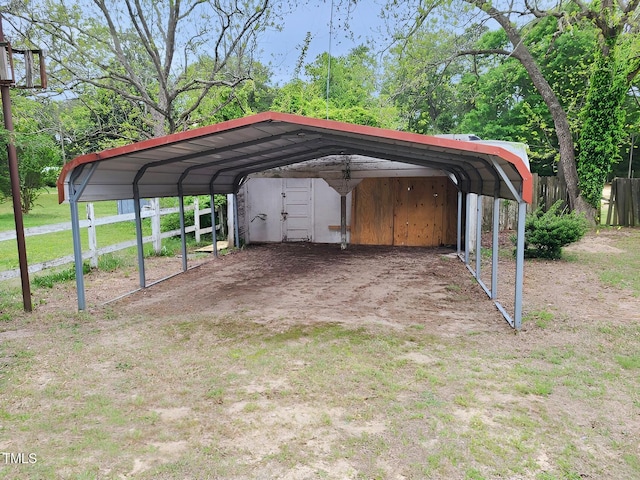 view of vehicle parking with fence and a detached carport