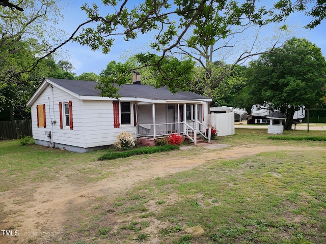 view of front of property with a chimney, fence, covered porch, and a front yard