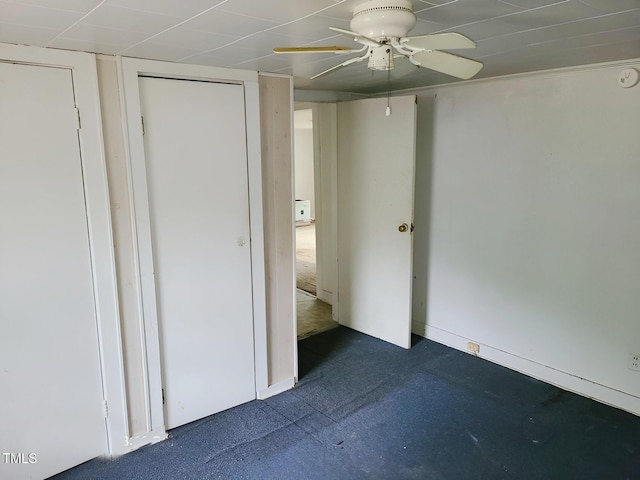 unfurnished bedroom with ceiling fan and dark colored carpet