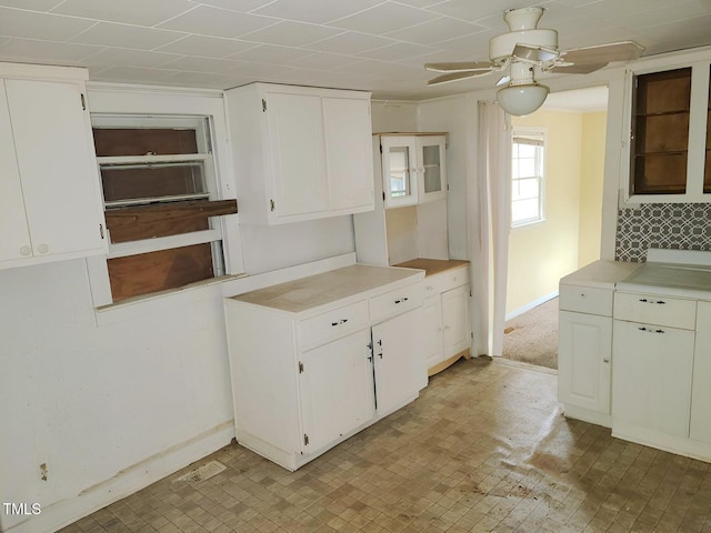 kitchen featuring light countertops, white cabinetry, baseboards, and ceiling fan