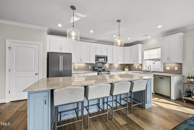 110 Deacon Ridge Ln, Youngsville, NC 27596 - kitchen with crown molding, decorative backsplash, a kitchen island, white cabinetry, and appliances with stainless steel finishes
