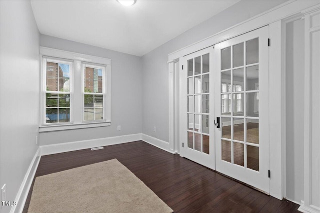 empty room with baseboards, visible vents, french doors, and dark wood-type flooring