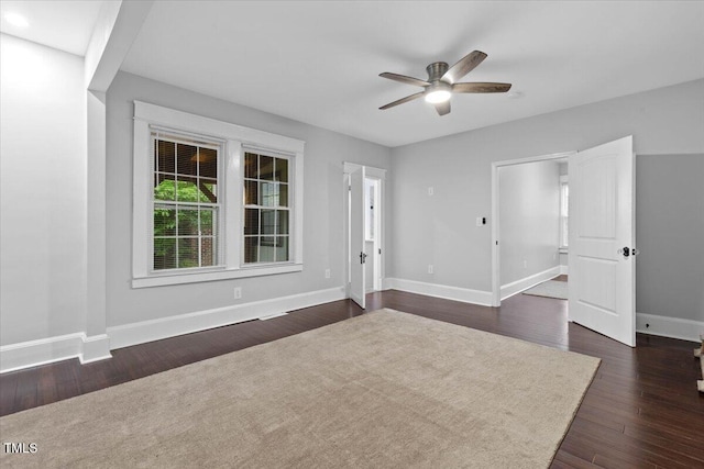 interior space with baseboards, a ceiling fan, and dark wood-style floors