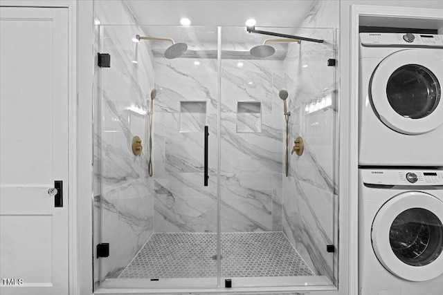 full bathroom featuring a marble finish shower and stacked washer and clothes dryer