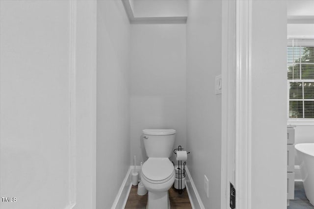 bathroom featuring baseboards, wood finished floors, and toilet