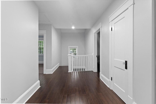 hallway featuring baseboards, dark wood finished floors, and an upstairs landing
