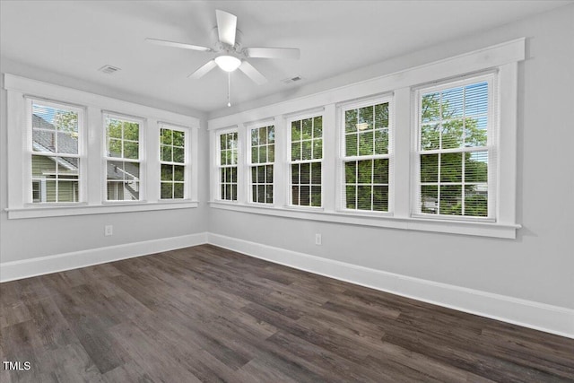 unfurnished sunroom with baseboards, wood finished floors, a healthy amount of sunlight, and visible vents