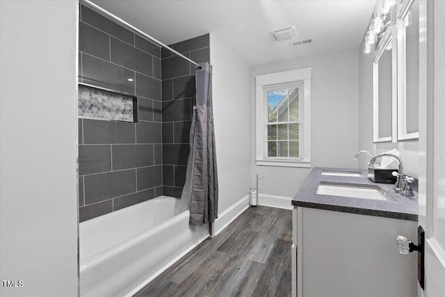 full bath with shower / bath combination with curtain, visible vents, wood finished floors, a sink, and baseboards