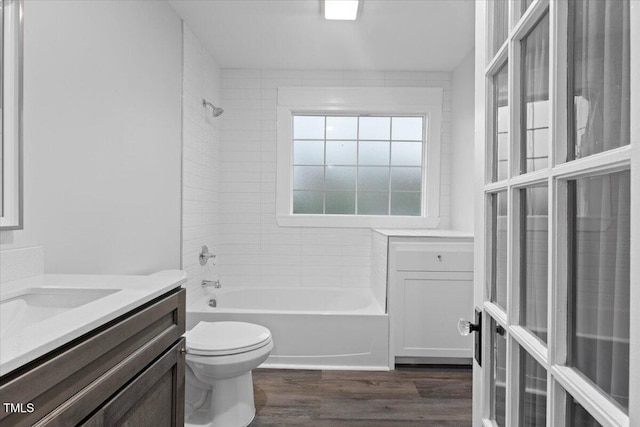 full bath featuring vanity, bathtub / shower combination, toilet, and wood finished floors