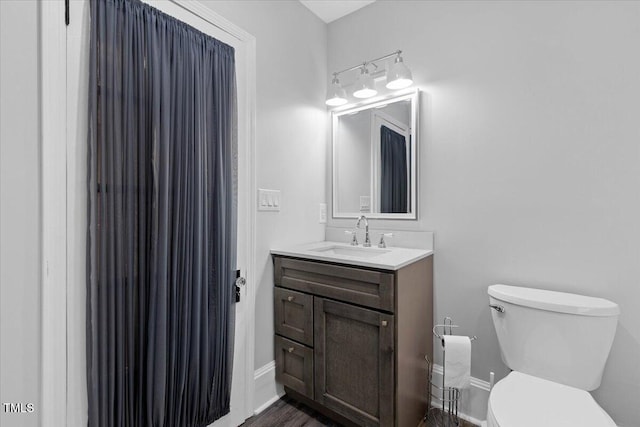 bathroom with vanity, baseboards, wood finished floors, and toilet