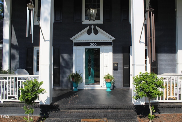 property entrance featuring a porch and brick siding