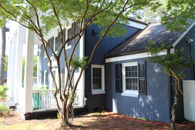 view of side of home featuring brick siding and roof with shingles