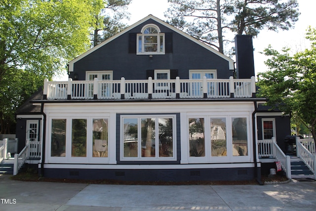 rear view of property with a balcony, a chimney, and crawl space