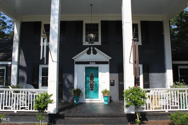 entrance to property with a porch and brick siding