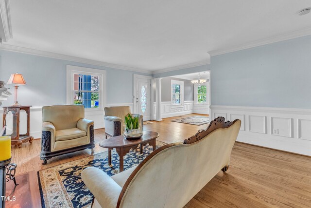300 S Pine St, Benson, NC 27504 - living room featuring crown molding, wood finished floors, a chandelier, a wainscoted wall, and decorative columns