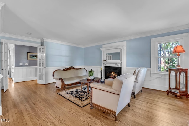 300 S Pine St, Benson, NC 27504 - living room with light wood-style floors, a warm lit fireplace, a wainscoted wall, and ornamental molding