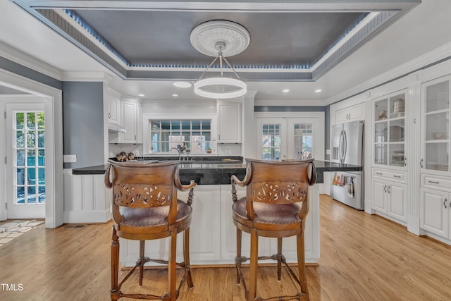 300 S Pine St, Benson, NC 27504 - kitchen with stainless steel fridge with ice dispenser, dark countertops, white cabinetry, light wood-style flooring, and crown molding