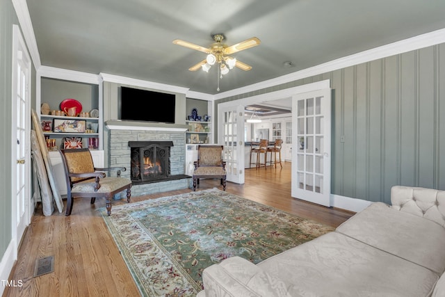 300 S Pine St, Benson, NC 27504 - living room with french doors, a ceiling fan, wood finished floors, a stone fireplace, and ornamental molding