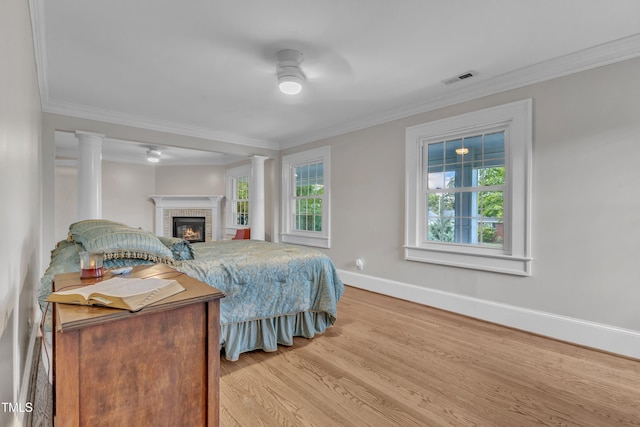 300 S Pine St, Benson, NC 27504 - bedroom with wood finished floors, crown molding, a brick fireplace, ornate columns, and ceiling fan