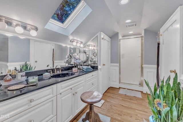 300 S Pine St, Benson, NC 27504 - bathroom featuring a skylight, vanity, a stall shower, a wainscoted wall, and wood finished floors