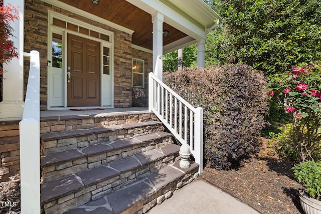 view of exterior entry featuring covered porch and stone siding