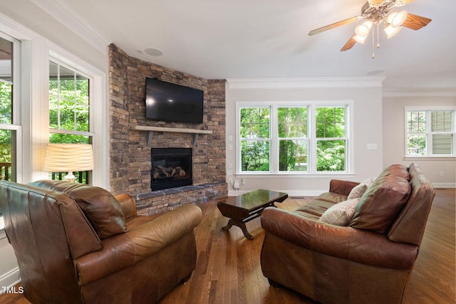 living room with crown molding, ceiling fan, a fireplace, baseboards, and wood finished floors