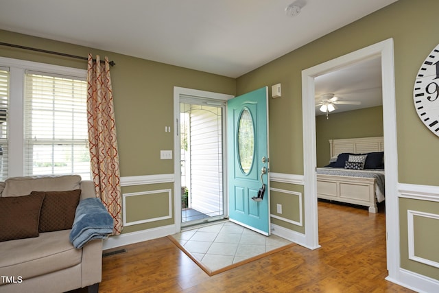 entrance foyer with a decorative wall, a ceiling fan, wood finished floors, and a wainscoted wall