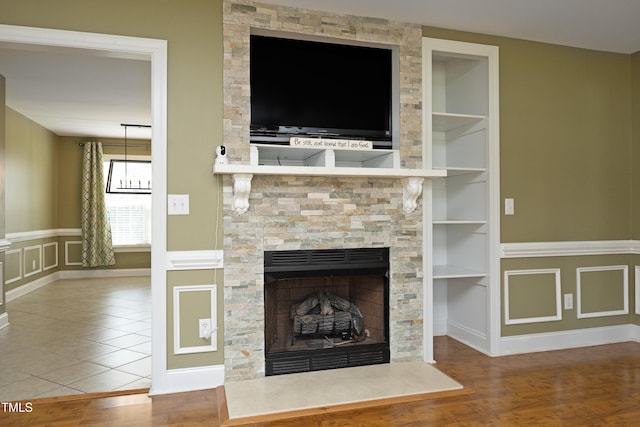 unfurnished living room featuring a decorative wall, a fireplace, wood finished floors, and built in shelves