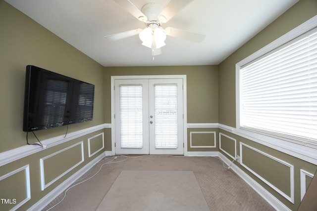interior space featuring french doors, carpet floors, a decorative wall, and a wainscoted wall