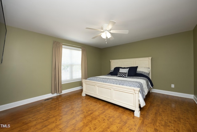 bedroom featuring a ceiling fan, baseboards, visible vents, and wood finished floors