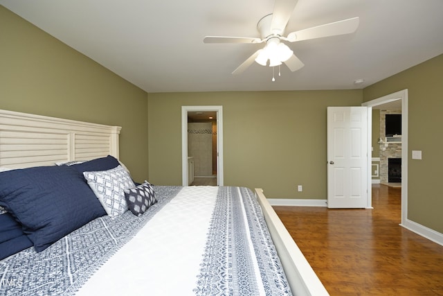 bedroom featuring baseboards, ceiling fan, a stone fireplace, and wood finished floors