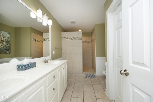 bathroom with tile patterned flooring, a sink, walk in shower, and double vanity