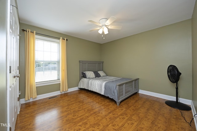 bedroom with baseboards, a ceiling fan, wood finished floors, and visible vents