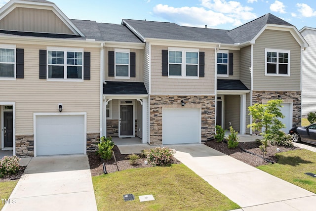 view of property featuring concrete driveway, stone siding, and an attached garage