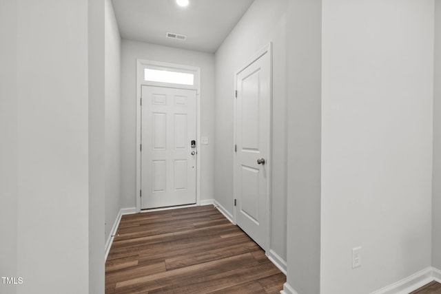 doorway with dark wood-type flooring and baseboards