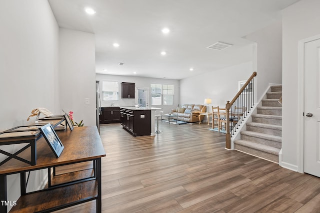 living area featuring stairway, light wood finished floors, and recessed lighting