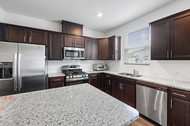kitchen featuring stainless steel appliances, dark brown cabinetry, light stone counters, backsplash, and recessed lighting