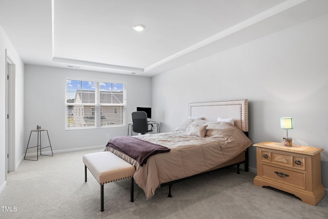 bedroom featuring light colored carpet, baseboards, and a tray ceiling