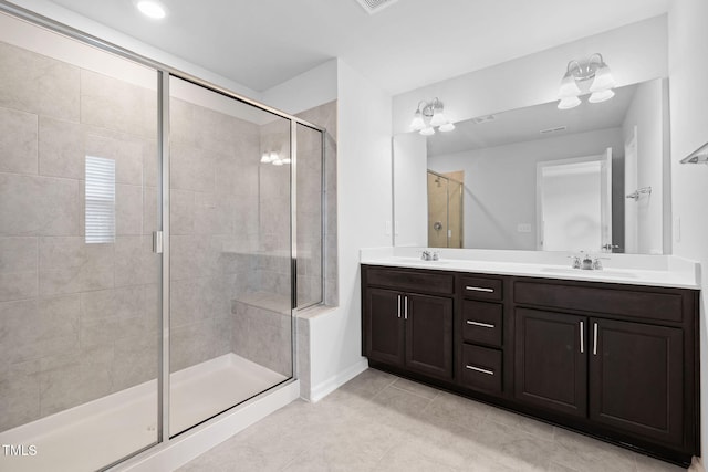 bathroom with a stall shower, double vanity, tile patterned flooring, and baseboards