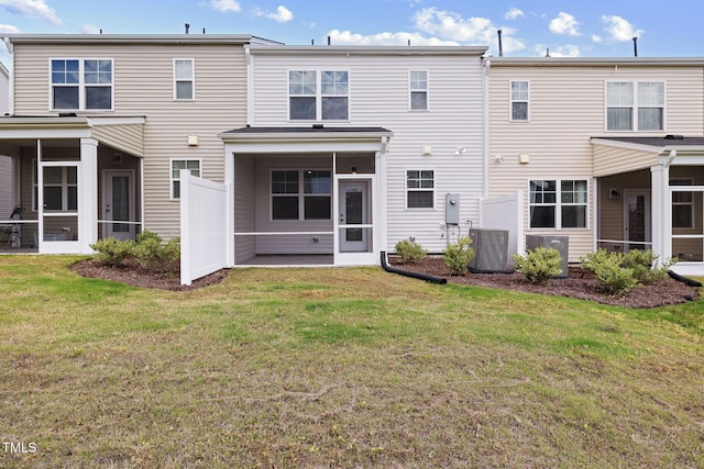 rear view of house featuring a sunroom, a lawn, and cooling unit