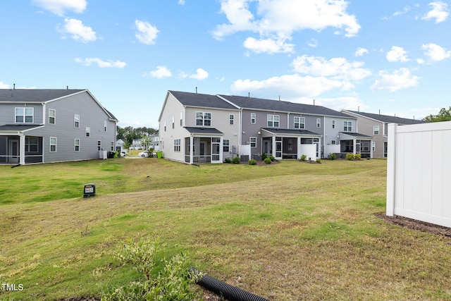 back of property featuring a sunroom, a residential view, and a lawn